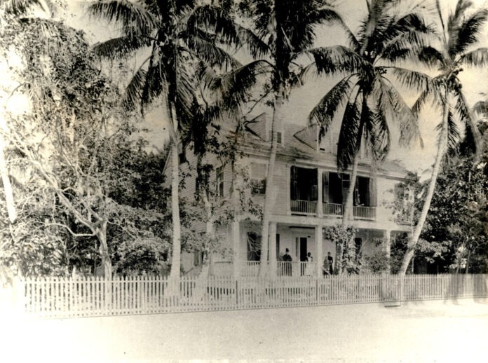 a large white house surrounded by palm trees