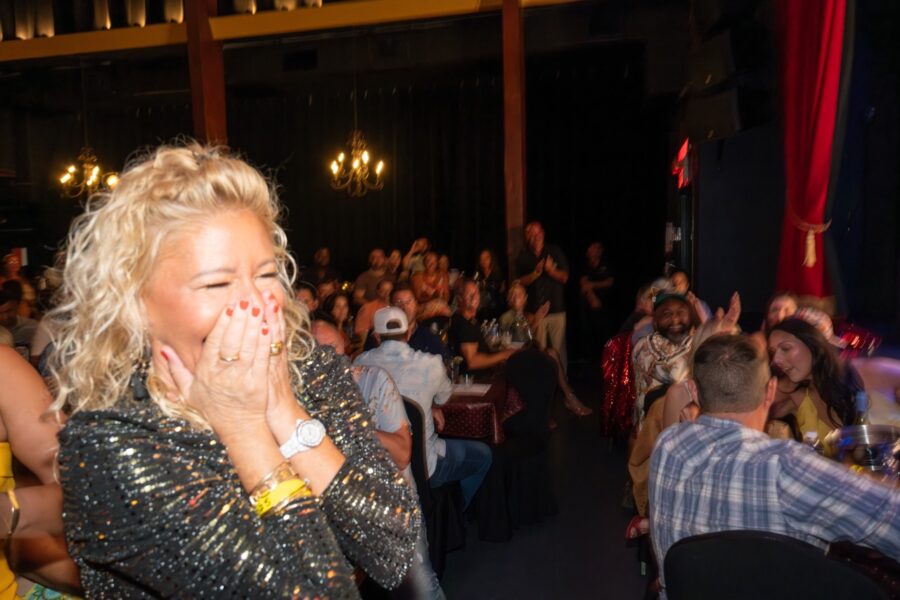 a woman covers her mouth as she stands in front of a crowd