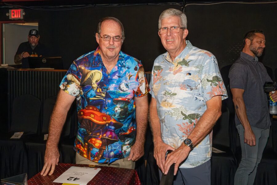 two men standing in front of a table with a cake on it
