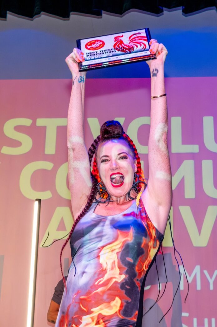 a woman holding up a trophy in front of a crowd