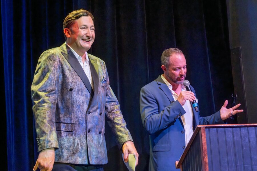 two men standing at a podium with a microphone