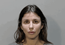 a woman in a gray shirt is looking at the camera