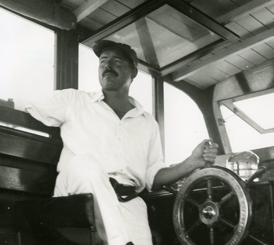 a man sitting on a boat steering a wheel