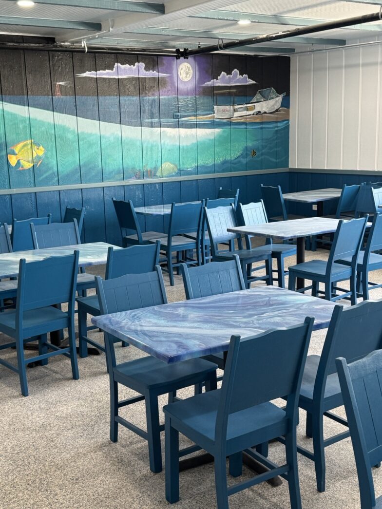 a dining room with blue chairs and a mural on the wall