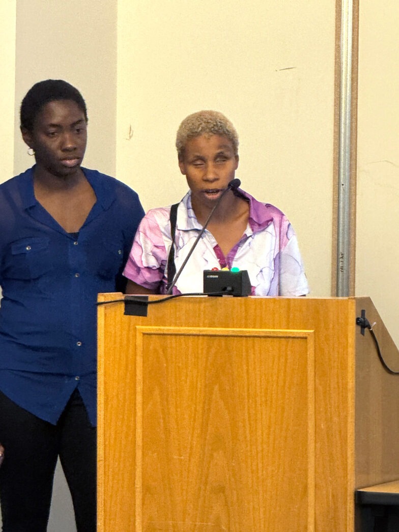 two women standing at a podium in front of a microphone