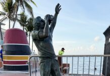 a statue of a boy reaching up to catch a frisbee