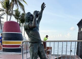 a statue of a boy reaching up to catch a frisbee