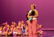 a woman standing on a stage in front of a group of children