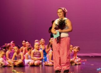 a woman standing on a stage in front of a group of children