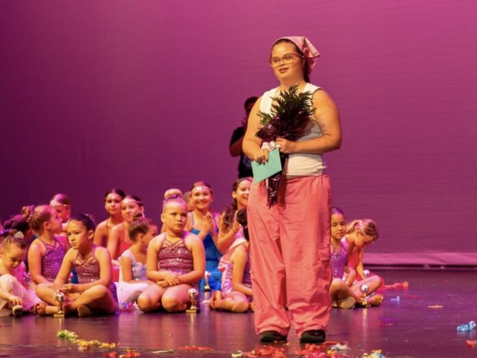 a woman standing on a stage in front of a group of children