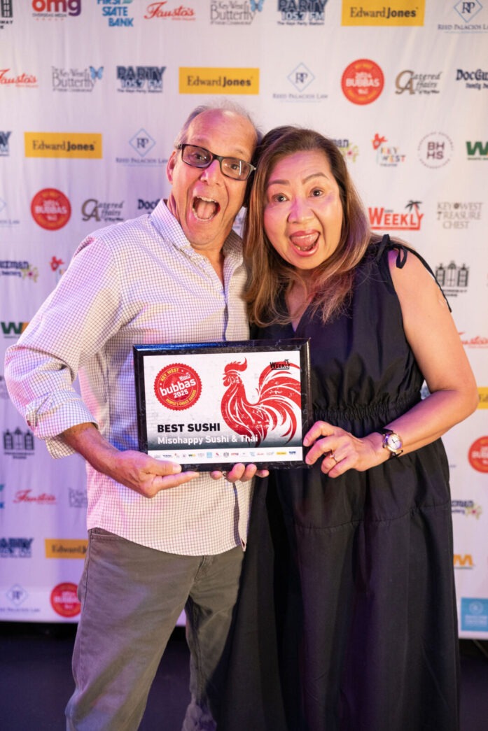 a man and woman posing for a picture while holding an award