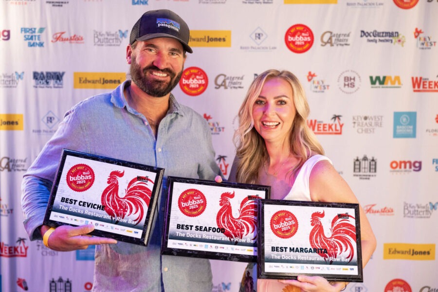 a man and a woman holding three awards
