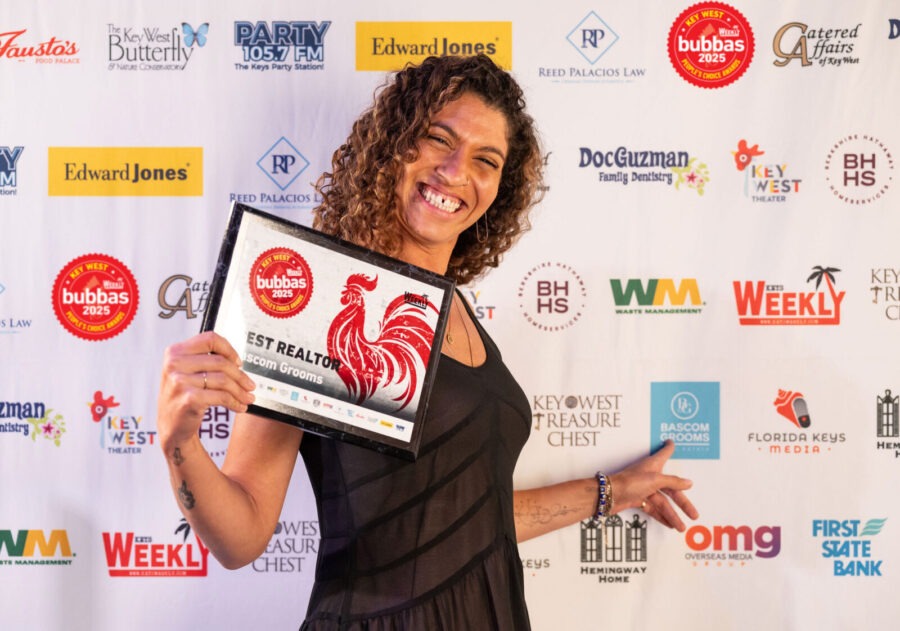 a woman holding a plaque in front of a red carpet