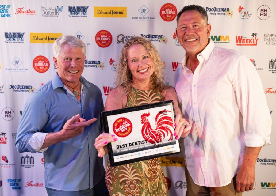 two men and a woman standing in front of a red carpet