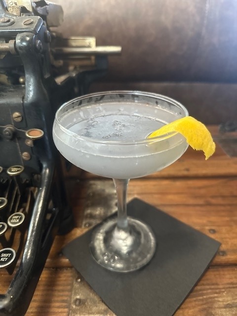 a drink sitting on a table next to an old typewriter