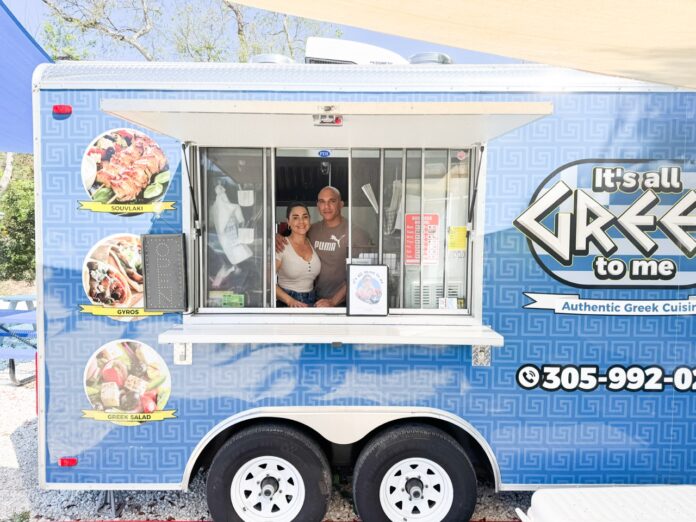 a woman and a man standing in the window of a food truck