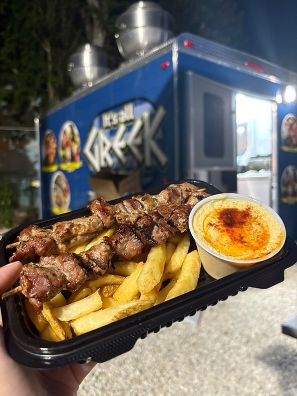 a person holding a tray of food in front of a food truck