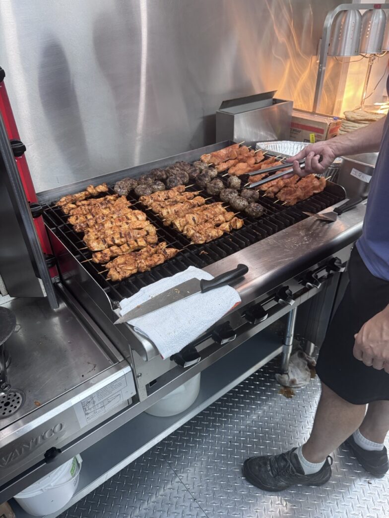 a man standing in front of a grill filled with food