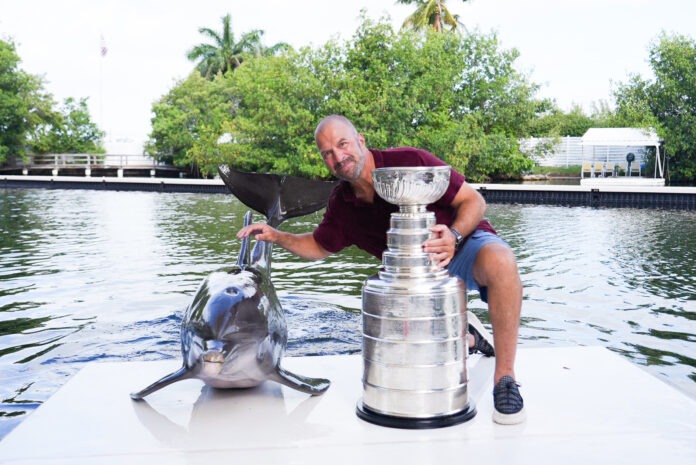 Zito, Stanley Cup and dolphin a man kneeling down next to a trophy on top of a boat