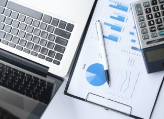a desk with a calculator, laptop and pen