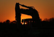 a tractor is silhouetted against the setting sun