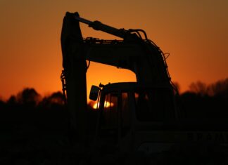 a tractor is silhouetted against the setting sun