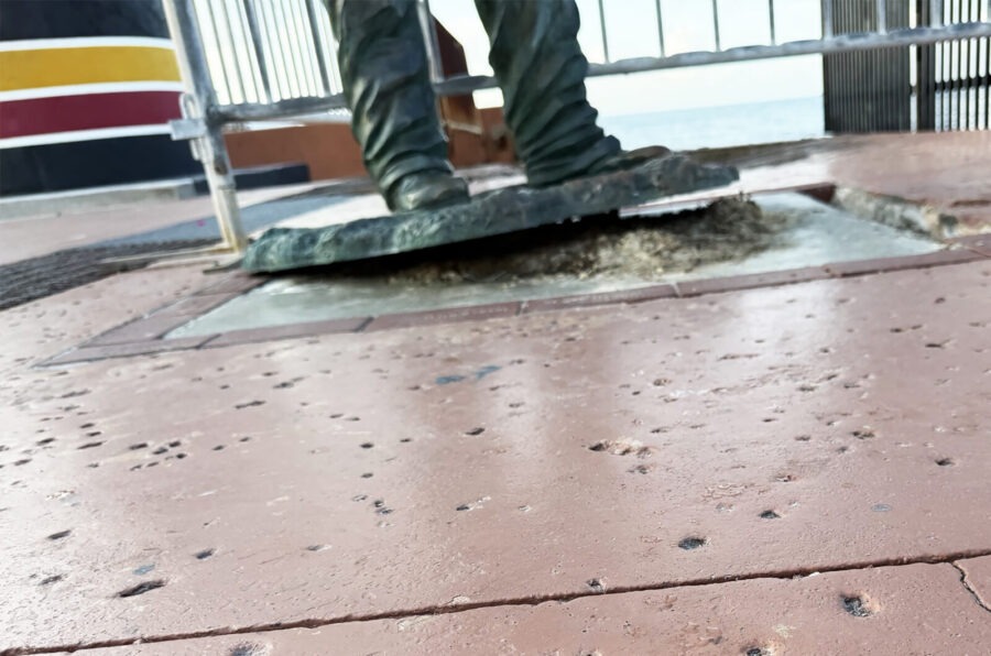 a statue of a person standing on top of a sidewalk