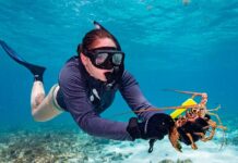 a woman scubas in the ocean with a lobster