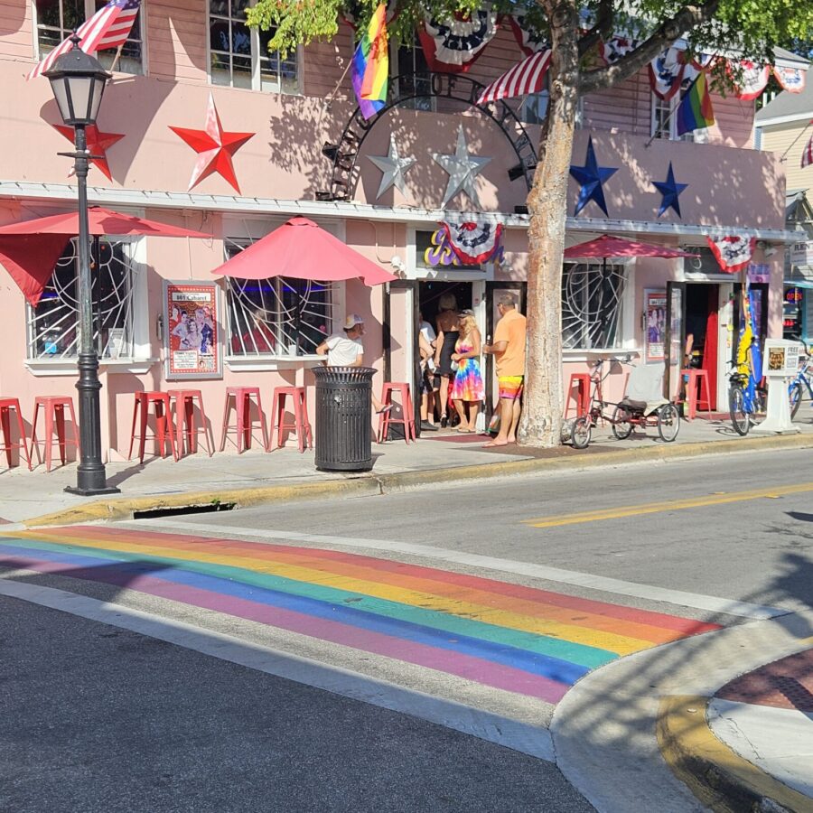 a rainbow painted street in front of a pink building