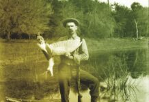 a man sitting on a boat holding a fish