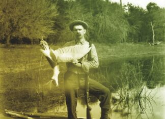 a man sitting on a boat holding a fish