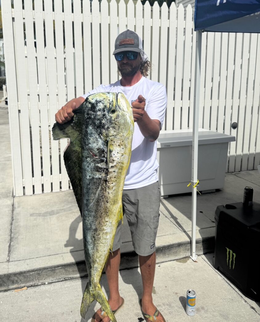 a man holding a large fish on a sidewalk