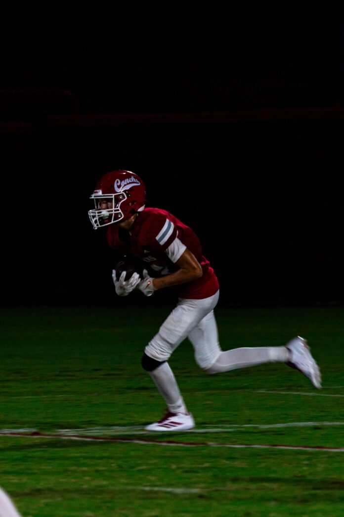 a football player running on a field at night