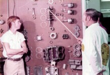 a couple of men standing next to each other in front of a wall