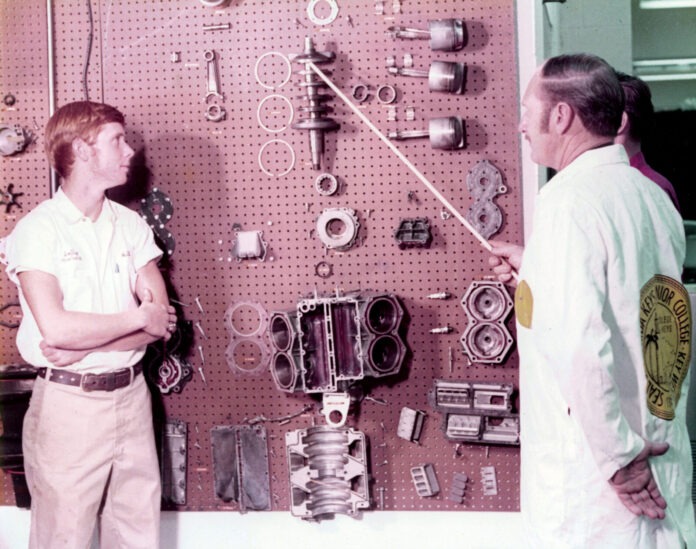 a couple of men standing next to each other in front of a wall