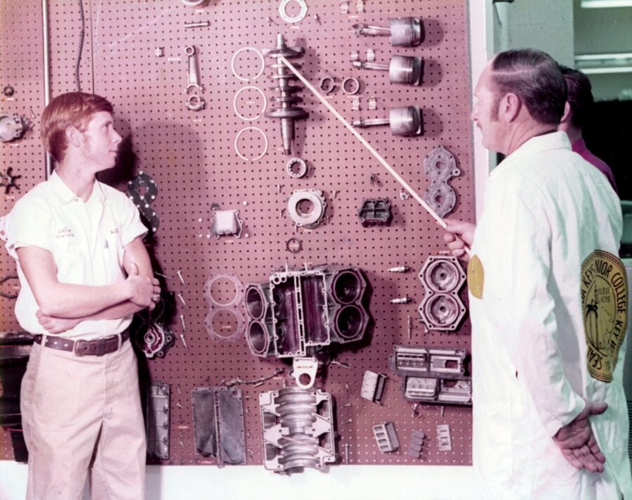 a couple of men standing next to each other in front of a wall