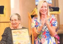 a woman holding an award standing next to an older woman