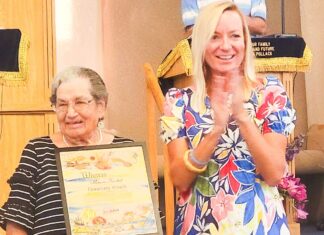 a woman holding an award standing next to an older woman