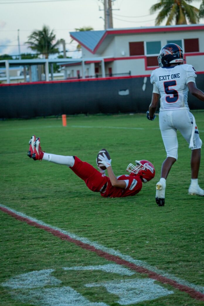 a football player dives for the ball as another player dives for the ball