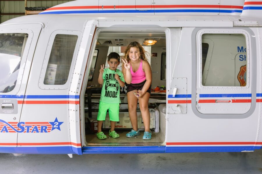 a couple of kids standing in the doorway of a helicopter