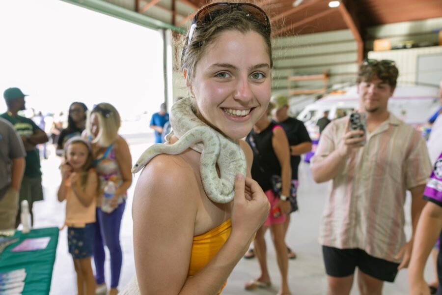 a woman holding a snake in front of a group of people