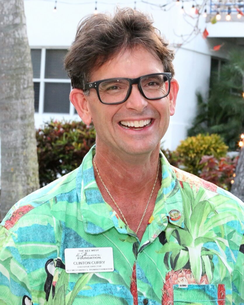 a man in a hawaiian shirt smiles at the camera