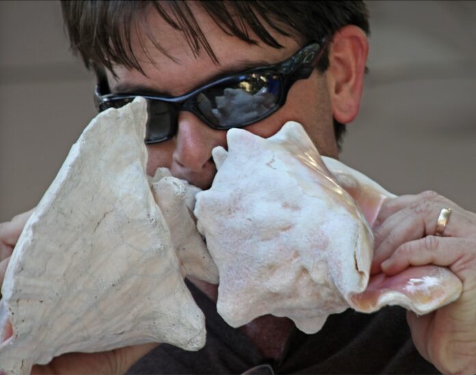 a man wearing sunglasses and a black shirt is holding a white object in his hands