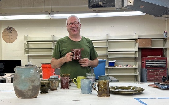 a man holding a mug standing in front of a table