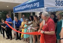a group of people standing around a ribbon cutting
