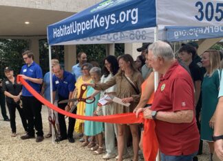 a group of people standing around a ribbon cutting