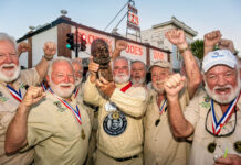 a group of men standing next to each other holding up medals