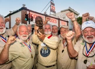 a group of men standing next to each other holding up medals