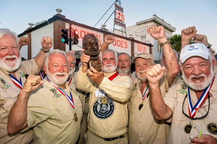 a group of men standing next to each other holding up medals