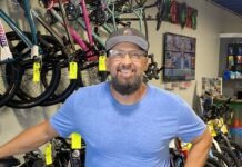 a man standing in a bike shop with his hands on his hips